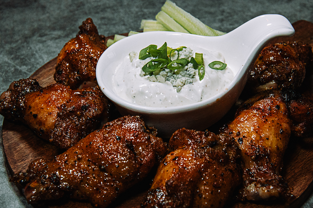 spicy pepper Buffalo wings on wooden platter with gorgonzola dipping sauce