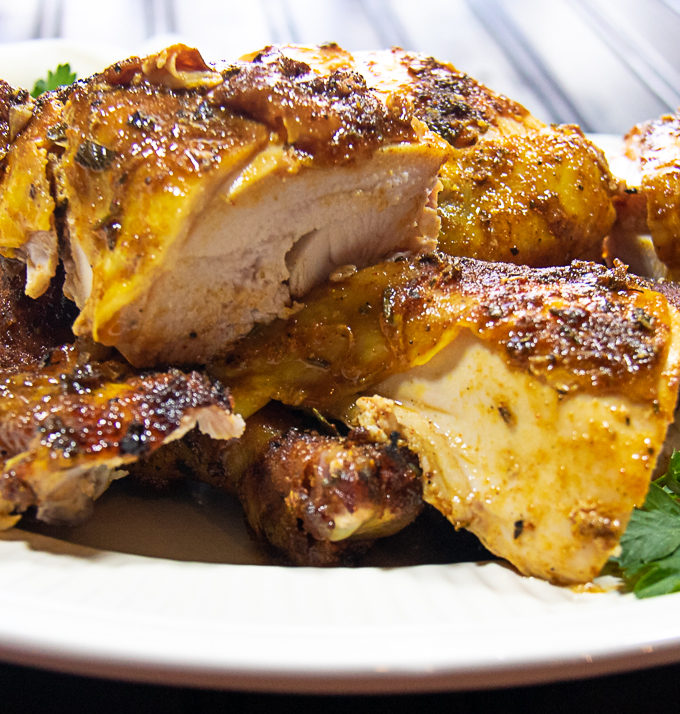 grilled rotisserie-style whole chicken cut into pieces on platter