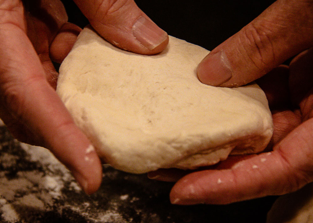 homemade garlic naan bread dough stretching with fingers
